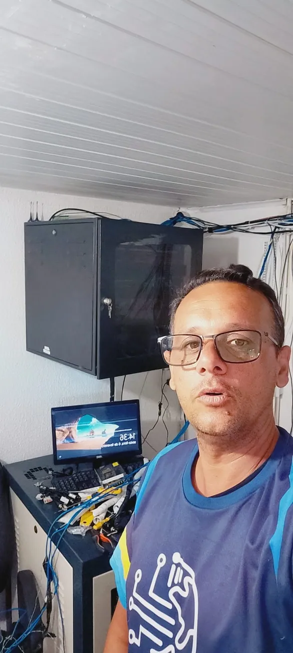 Técnico ao lado de rack com equipamentos de rede e CFTV